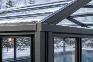 Close-up of powder-coated aluminium structural framing supporting a glass pool enclosure during winter.
