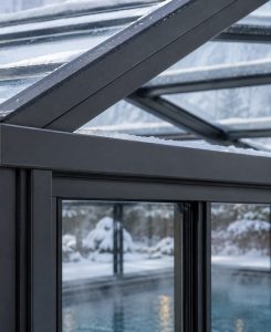 Close-up of powder-coated aluminium structural framing supporting a glass pool enclosure during winter.